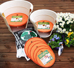 Staged gardening scene with multiple orange Ups-A-Daisy inserts, pots, potting soil bag and flowers on wood deck.