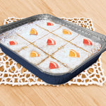 Blue-handled-looking 13x9 meal pan filled with powdered dessert squares on a doily