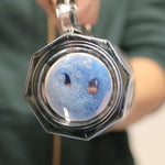 Blue smiling Scrub Daddy sponge seen through the end of a glass or jar, top-down close-up