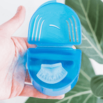 Open blue storage case held in a hand containing a translucent molded dental guard inside the lower compartment