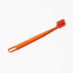 Single orange Boie toothbrush with slim handle and soft bristle head on white background.