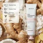 BOKA toothpaste tube on coconut flakes and ginger with icons and a panel listing fluoride-free, paraben-free, SLS-free, cruelty-free, vegan