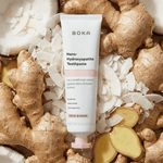BOKA Nano-Hydroxyapatite toothpaste tube placed on a bed of coconut flakes and ginger roots, highlighting coco ginger flavor