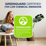 Greenguard certification badge over a living room scene with woman on couch and hardwood floor promoting low chemical emissions