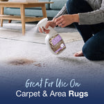 Hand holding and spraying a Bona Pet System bottle onto a stained light-colored carpet, product label visible