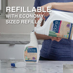Person pouring an economy-sized Bona refill into a smaller Bona spray bottle with refillable product text