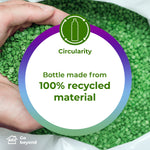 Circular badge over green plastic pellets stating 'Bottle made from 100% recycled material' with a hand holding pellets