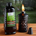 Mainstays citronella torch fuel bottle next to a lit decorative tabletop torch on wooden surface