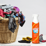 Lifestyle photo showing Bounce spray bottle beside a laundry basket overflowing with clothes on a neutral surface