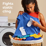 Woman examining a blue shirt with socks and a laundry basket in front of a washing machine, illustrating static cling.