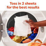 Hand dropping two white dryer sheets into a front-loading dryer full of colorful clothes; headline reads “Toss in 2 sheets.”