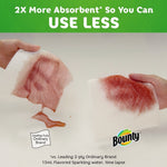 Two paper towel pieces soaking up red liquid in a side-by-side absorbency comparison with Bounty logo and claim text