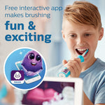Boy brushing with a turquoise Philips Sonicare kids toothbrush next to a graphic promoting a free interactive app and purple character.