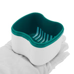 Hand holding open white braces case with teal interior tray featuring drainage slots, close-up view.