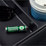 Breath Savers spearmint roll placed in a vehicle cupholder beside sunglasses and a paper cup