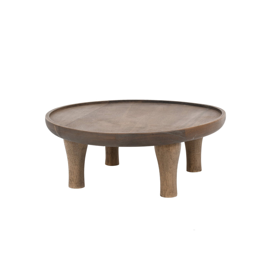 Low-angle view of a brown round wooden plant stand with four tapered legs on a white background