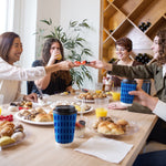 Group of people at a table enjoying brunch with Chinet Comfort blue patterned cups and lids visible on the table.