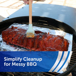 Basted rack of ribs on aluminum foil inside a grill while a brush applies sauce
