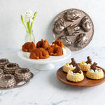 Kitchen display with a bunny-shaped cake pan, baked bunny cakes on a cake stand and additional serving pieces