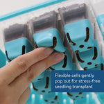 Close-up of a hand pressing a blue silicone cell to pop out soil from a Burpee SuperSeed tray with inset caption