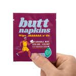 Hand holding a maroon single-use Butt Napkins sachet showing brand name, runner graphic and size information
