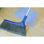 Angled view of blue broom head and translucent dustpan on a wood floor, showing bristles and joint