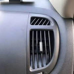 Close-up of a vehicle air vent with a small vent stick clipped to a vertical slat, showing typical dashboard texture