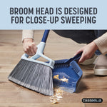 Person using Casabella broom and dustpan to sweep crumbs into the dustpan, showing close-up sweeping action