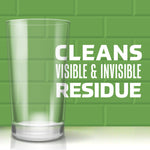 Clear drinking glass on green tiled backdrop with bold text stating cleans visible & invisible residue