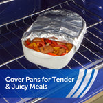White ceramic baking dish covered with aluminum foil on an oven rack, revealing roasted vegetables inside.