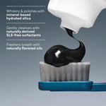 Close-up of black charcoal toothpaste being squeezed onto a blue toothbrush head with callouts about mineral-based hydrated silica and SLS-free surfactants.