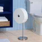 Charmin Forever Roll on a freestanding stainless steel holder positioned next to a toilet and shelving in a bathroom scene.