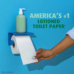 Hand pulling a sheet from a toilet-roll-style dispenser with a lotion pump on top and bold text about lotioned toilet paper.