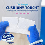 Two blue furry hands tearing a sheet of Charmin Ultra Soft toilet paper under the headline 'Cushiony Touch' with the Charmin logo visible.