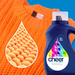 Close-up of an orange knit sweater with a cheer colorguard detergent bottle and a textured fiber droplet graphic