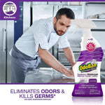 Chef wiping a stainless steel surface with a large OdoBan lavender spray bottle shown prominently in the foreground.