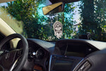 Chemical Guys Black Frost drip-style air freshener hanging from a rearview mirror inside a car, showing dashboard and steering wheel.