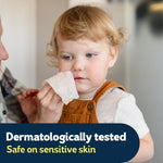 Toddler having face wiped with a tissue, overlay text about dermatologically tested and safe on sensitive skin