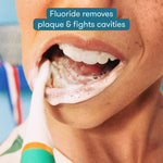Close-up of child brushing with foamy toothpaste, text overlay about fluoride fighting cavities
