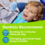 Smiling child reclined in a dental chair with a dentist's gloved hands visible and brushing recommendations text