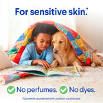 Child reading under a colorful quilt next to a golden retriever with copy reading 'For sensitive skin' and icons for no perfumes or dyes.