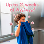 Child smelling a blue garment indoors with floating cherry blossom graphics and text about weeks of freshness
