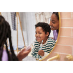 Child smiling into a bathroom mirror while holding a kids electric toothbrush