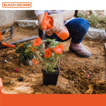 Close-up lifestyle image of a child spraying an orange toy spray bottle over a potted flower in dirt, Black+Decker logo band at top.