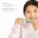 Child brushing teeth with a green toddler toothbrush, accompanied by on-image text describing soft bristles