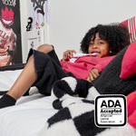 Child reclining on bed using a white electric toothbrush with an ADA Accepted badge visible in the corner
