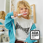 Child brushing with a white Made By Dentists electric toothbrush, bathroom mirror in background and ADA Accepted badge.