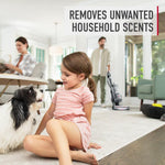Lifestyle scene with a child sitting on a carpet and a dog while a person vacuums in the background