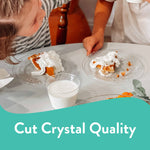 Two clear Chinet dessert plates on a table with slices of pie, a glass of milk and children leaning in above