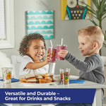 Two children clinking clear Zoo Pals cups filled with smoothies while other cups and sandwiches sit on the table.